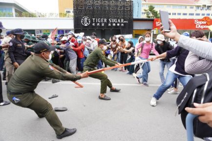 A Phnom Penh district guard tries to pull part of a barricade away from a NagaWorld worker during the strike on August 11, 2022. (Hean Rangsey/VOD)