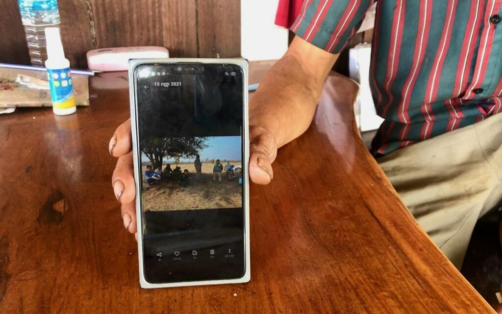 Koy Lei shows reporters photos of cadastral officers who came to measure his land in early 2021. (Fiona Kelliher/VOD) 