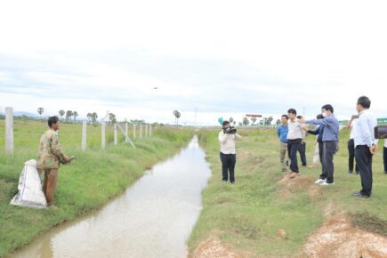 Government officials pointing at barbed wire fencing along the Phnom Penh-Sihanoukville expressway. (Ministry of Transportation)