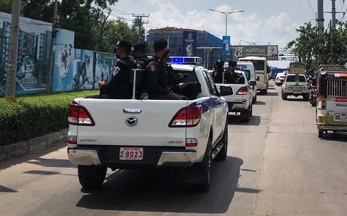Armed police escort a convoy of buses carrying foreign nationals from a Phnom Penh apartment block to the city’s airport on October 13, 2022. (Michael Dickison/VOD)