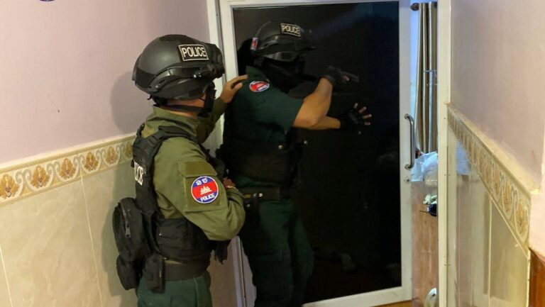 A Koh Kong officer armed with a handgun enters a door during a raid in Koh Kong, in a photo posted to the Koh Kong Provincial Police Facebook page on November 12, 2022.