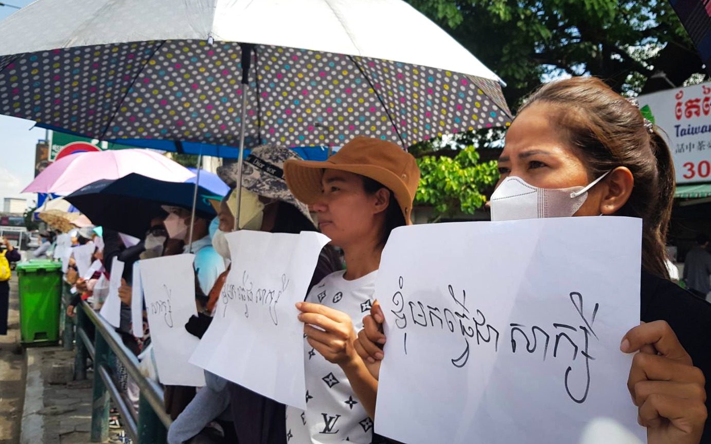 NagaWorld workers stand outside the Phnom Penh Municipal Court in support of unionists summoned for questioning on November 14, 2022. Their signs say, "I come to be a witness." (Tran Techseng/VOD)