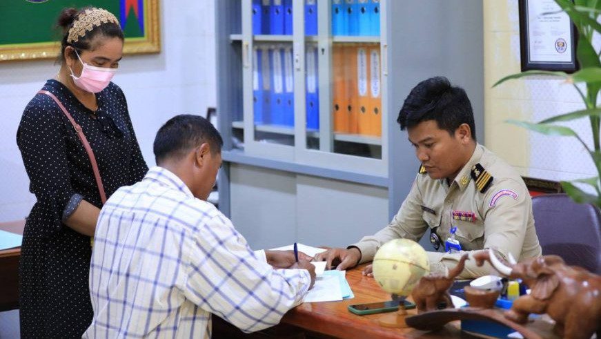 Banteay Meanchey civil servant Oeun Thy (center) signs a paper after his detention for criticizing rice prices, in a photo posted by the Banteay Meanchey Provincial Police on November 18, 2022.