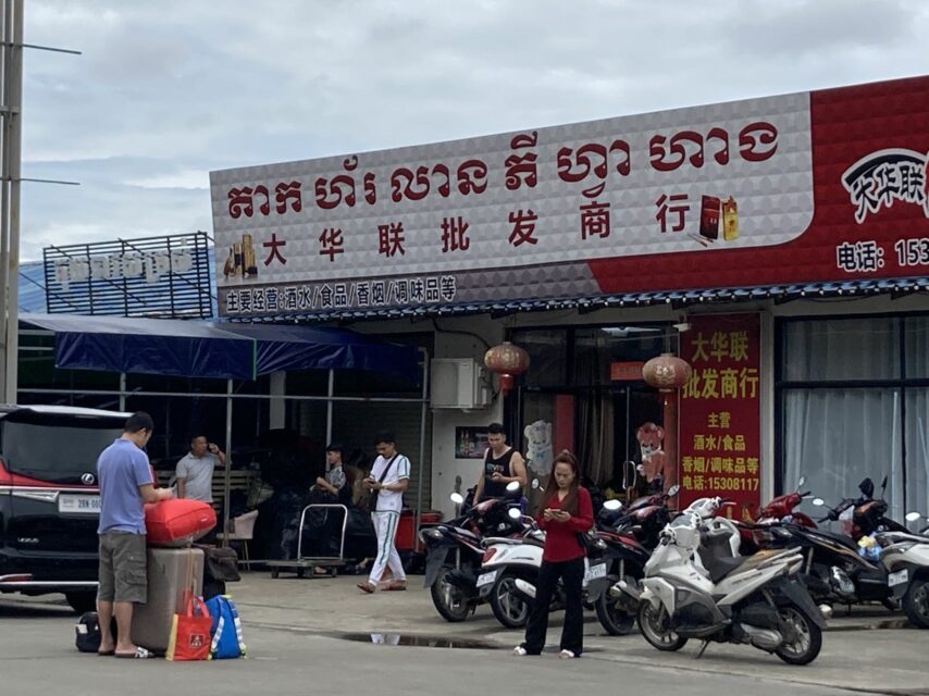 People, including some with luggage, stand outside a store in the Chinatown area in Sihanoukville's Buon commune on September 19, 2022. (Yan Huang/VOD)