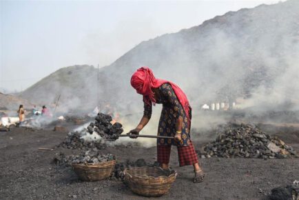 A child coal scavenger burns coal before selling it for use at a depot in a mining area of Jharia coalfield, India, November 11, 2022. (Tanmoy Bhaduri/Thomson Reuters Foundation)