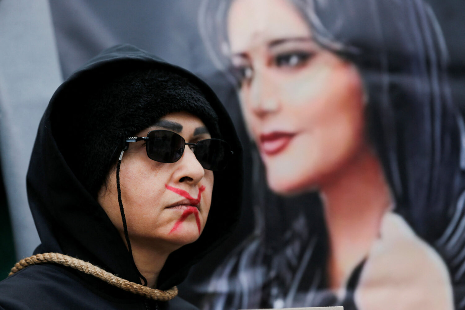 A poster of Mahsa Amini, who died in Iran after morality police took her into custody for wearing her hijab too loosely, is raised at a protest in Istanbul on December 10, 2022. (Dilara Senkaya/Reuters)