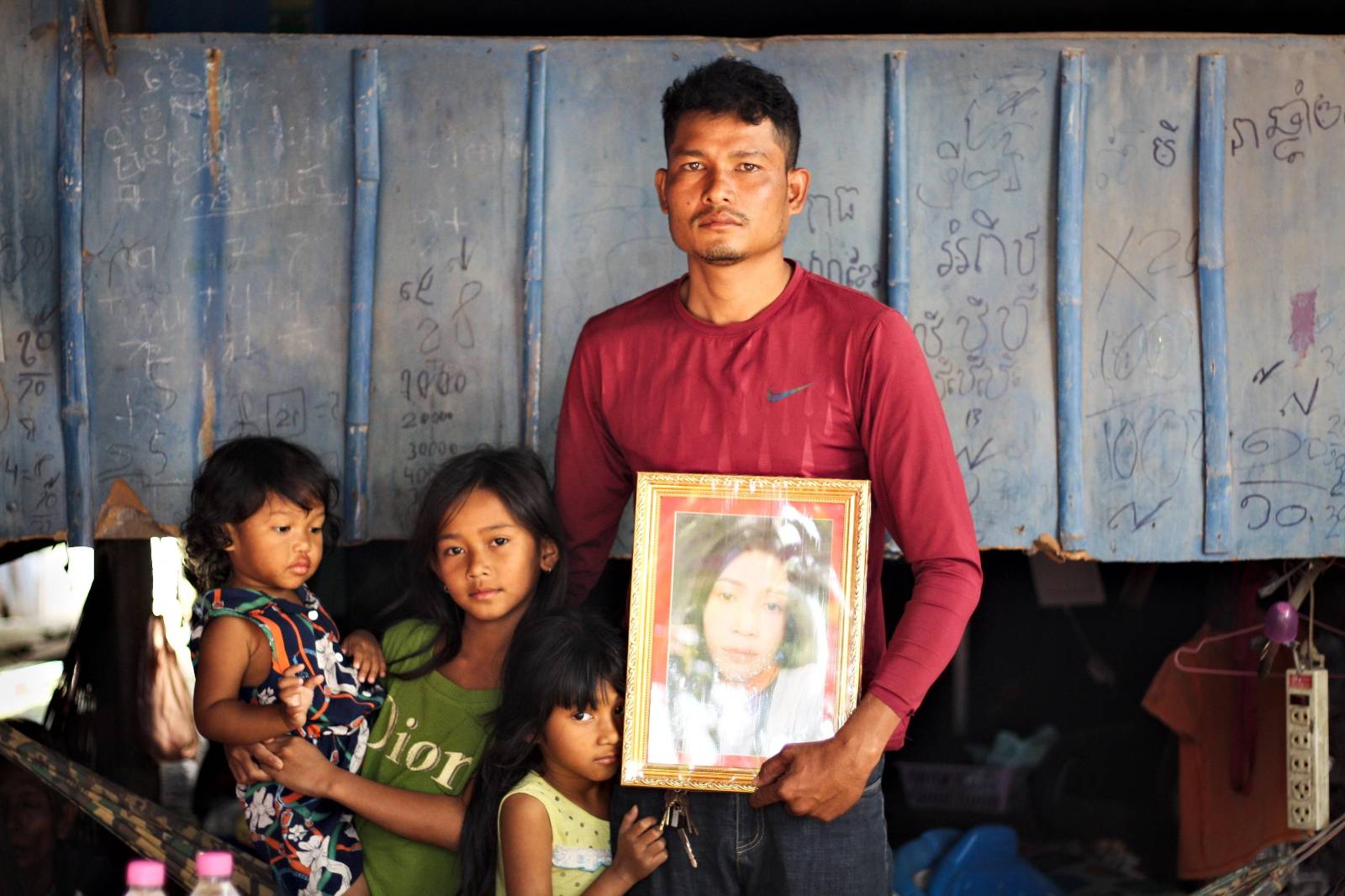 Khim Vong holds a photograph of his wife, Sam Sreymom, who is missing after a fire at the Grand Diamond City Casino, with the couple's three children on December 31, 2022. (Michael Dickison/VOD)