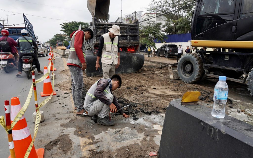 Construction workers fix the road damaged by a bulging pope moving sand under National Road 2. (Hean Rangsey/VOD)