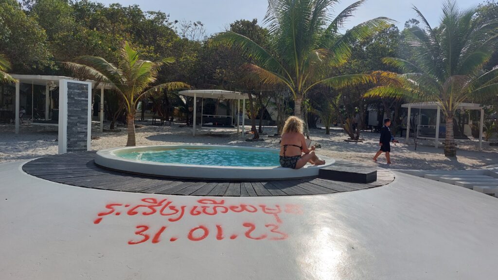 A tourist reads on the edge of a pool that's been marked by authorities as condemned at Moonlight Resort on Koh Rong Sanloem island on February 4, 2023. (Danielle Keeton-Olsen/VOD)