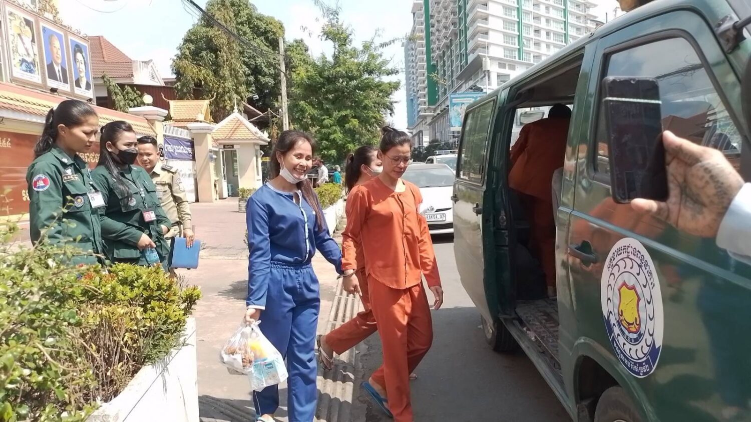 Lanh Thavry (left) and Kim Tola hold hands as they walk out of Phnom Penh Municipal Court and into a prison van on February 6, 2023. (Ouch Sony/VOD)