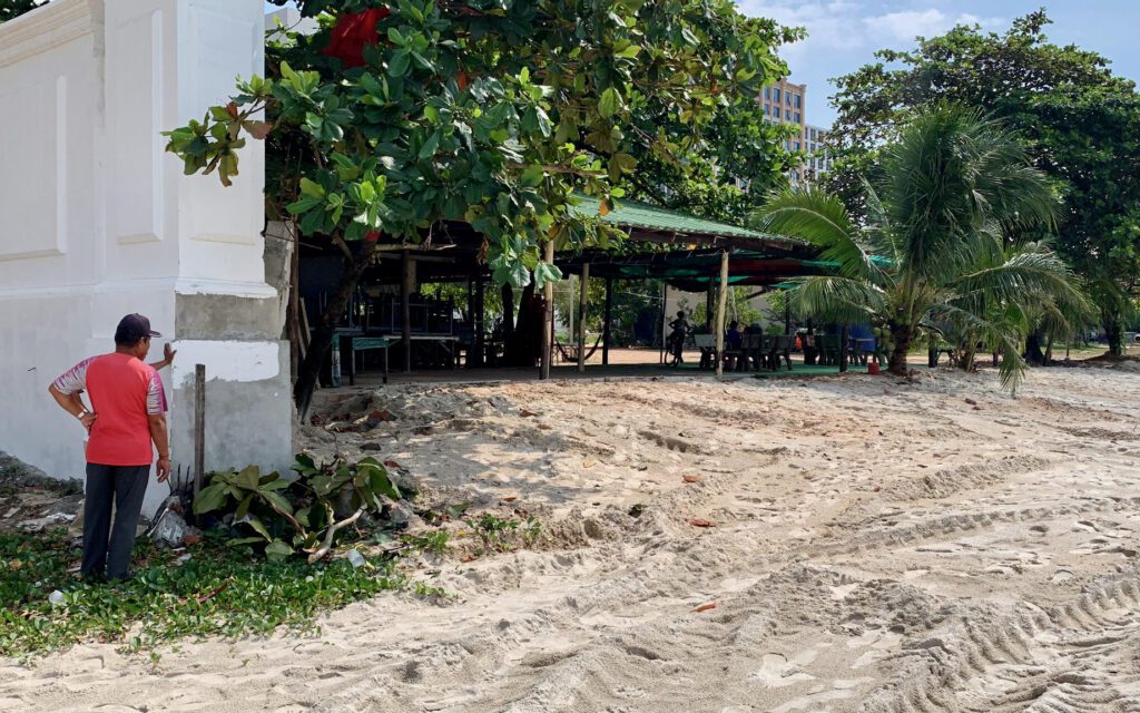 A person peers into a compound on Sihanoukville's O'Chheuteal beach, which was previously walled off. (Supplied)